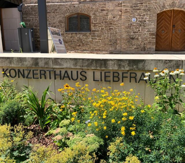 Eingangsbereich mit Beschriftung "Konzerthaus Liebfrauen" in Wernigerode, im Vordergrund ein Blumenbeet, dahinter der Schriftzug